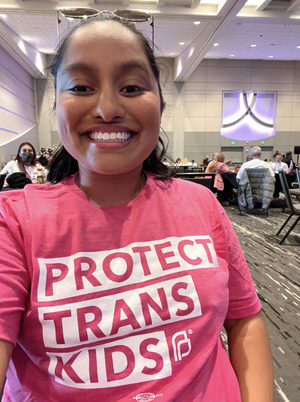 Indira D'Souza wearing a pink shirt that says "Protect Trans Kids"