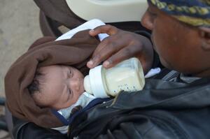 A person feeds a baby a bottle