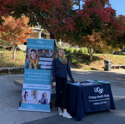  Danielle Van Liefde posing next to a UCSF banner and table, recruiting students for the study at Cabrillo College in Santa Cruz